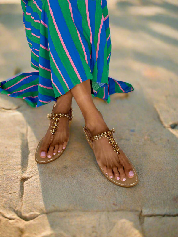 tan sparkly flat leather sandals on feet with blue dress 