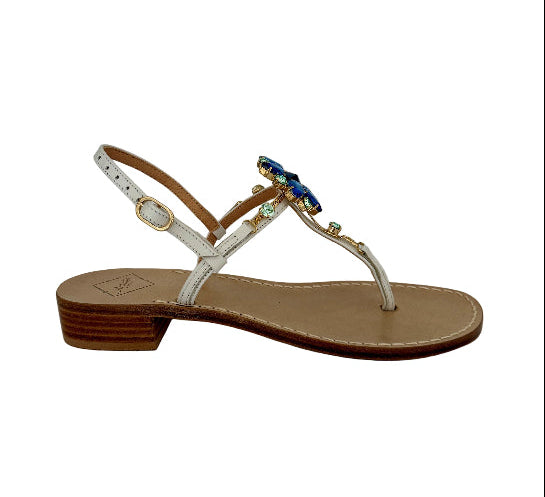 Single sandal with white straps and blue sparkly embellishments on a white background
