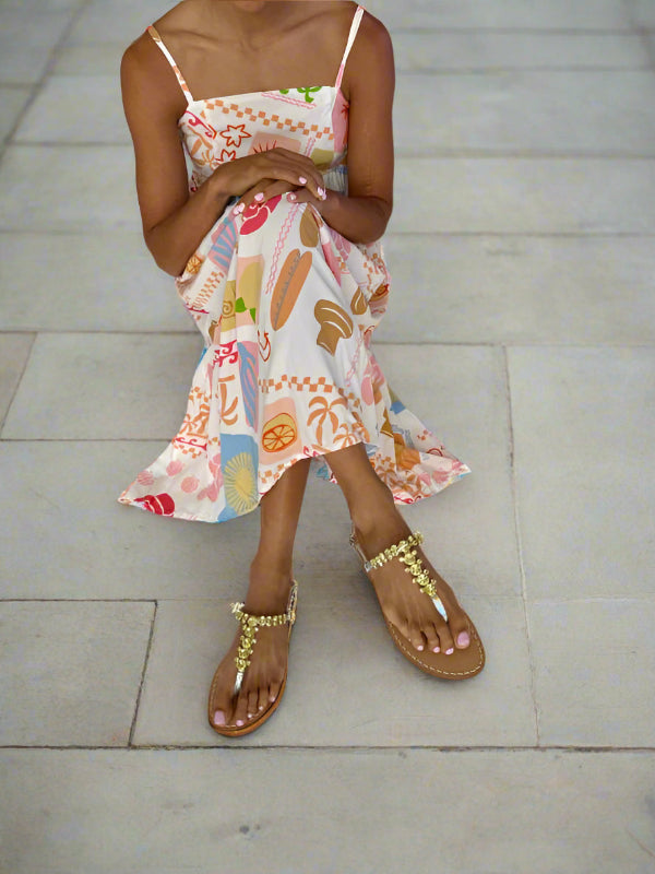 Woman wearing a pale colorful dress with sparkly silver yellow crystal flat sandals.