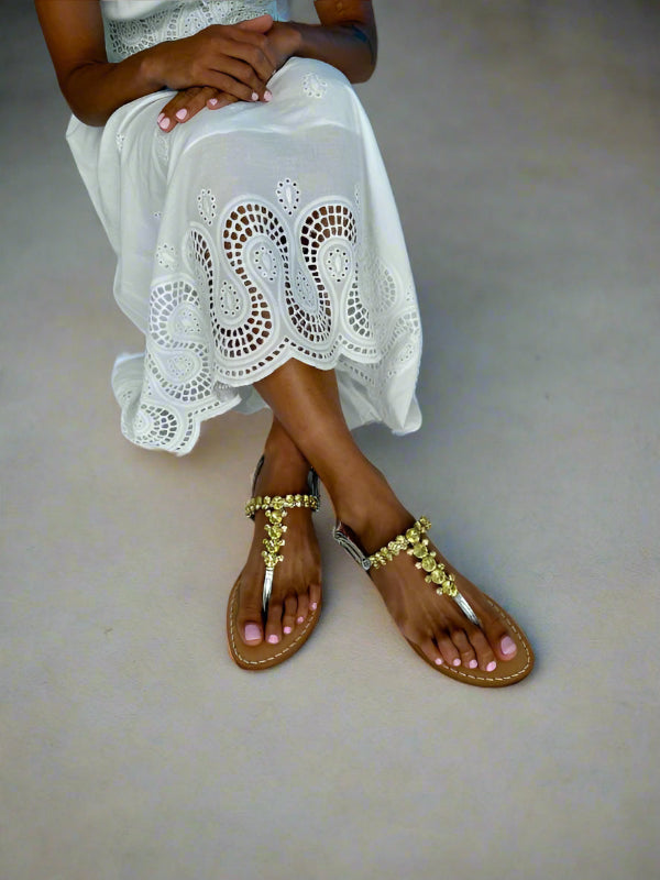 Lady wearing silver gold sandals and a white lace summer dress.