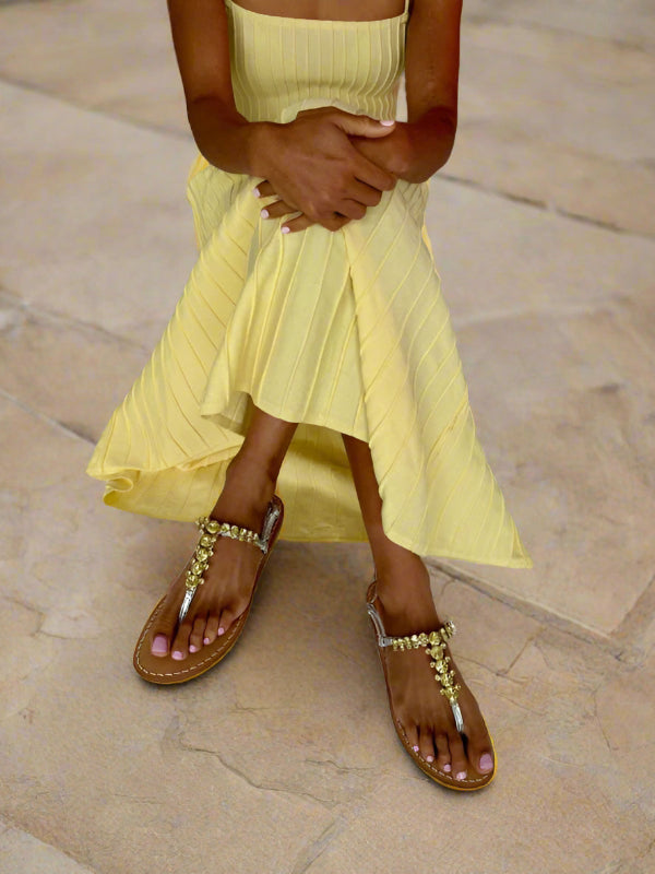 Woman wearing a yellow dress and silver sandals on a white background