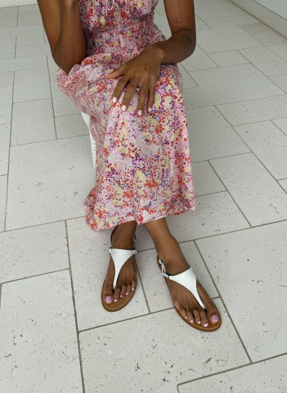 Lady wearing a floral dress and white flat sandals
