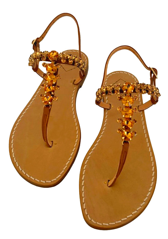 Pair of tan leather sandals with gold Swarovski crystal embellishments on a white background