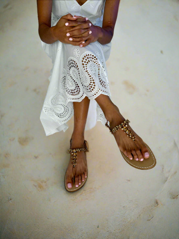 Lady wearing a white lace dress and tan sparkly flat sandals